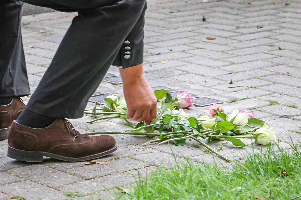 Ein Mann legt eine Blume an einem Gedenkstein ab