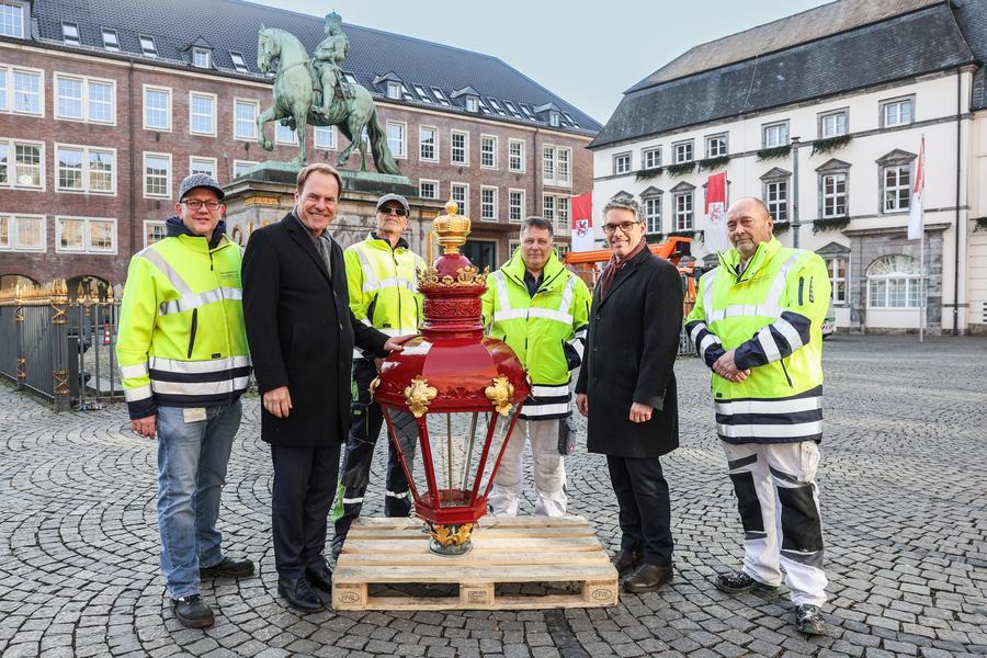 Oberbürgermeister Dr. Stephan Keller (2.v.l) und Torben Beisch, Geschäftsführer der Netzgesellschaft (2.v.r) präsentieren mit Mitarbeitern der Netzgesellschaft die frisch restaurierten Köpfe der Leuchten