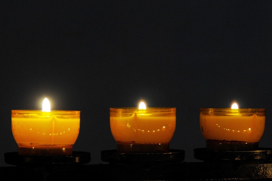 Drei Kerzen leuchten im Dunkeln