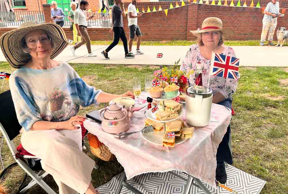 Zwei Frauen in englischem Outfit sitzen an einem Picknick-Tisch