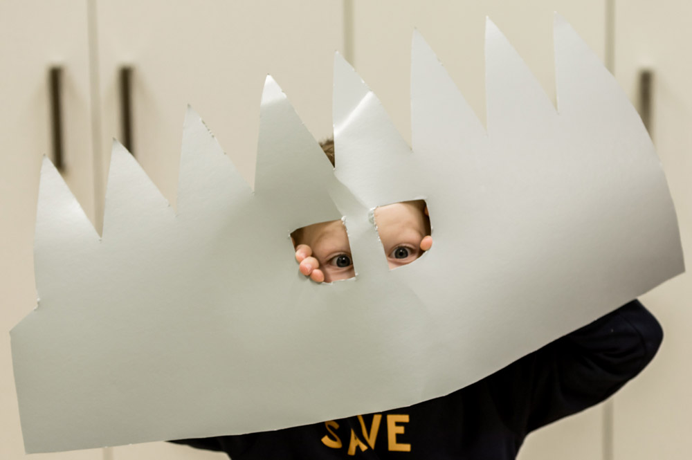 Kind mit gebasteltem Helm vor dem Gesicht