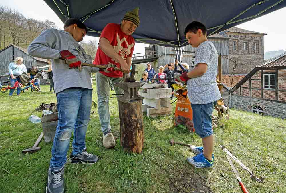 Erwachsener und zwei Jugendliche beim Schmiede-Workshop
