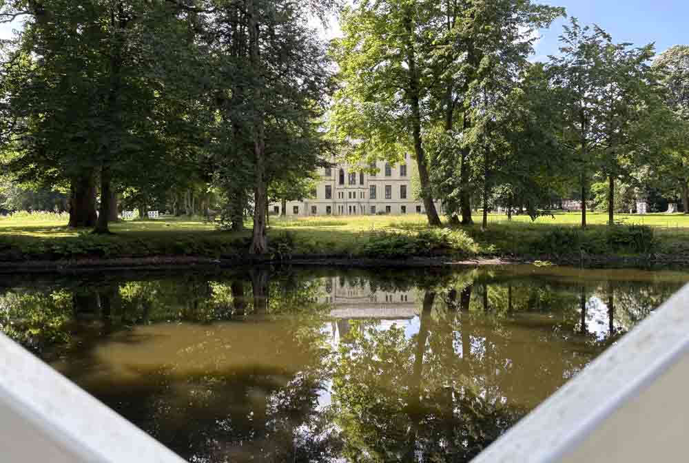 Schloss Evenburg mit Bäumen und See im Vordergrund