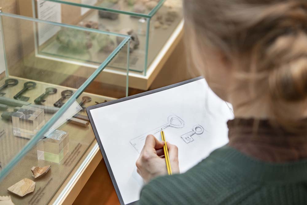 Frau zeichnet Schlüssel, die in einer Vitrine liegen