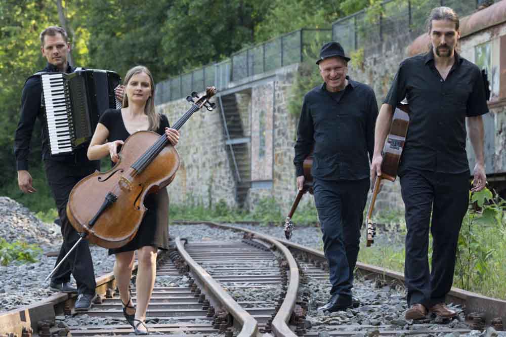 „Die Grenzgänger" laufen mit Instrumenten auf Gleisen