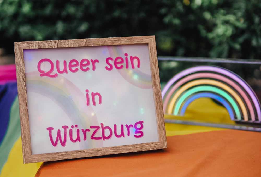 Schild mit dem Schriftzug "Queer sein in Würzburg"