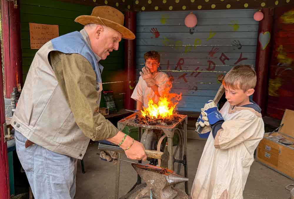 Kinder und Verantwortlicher beim Schmieden