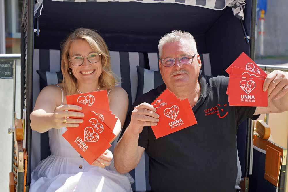 Die städtische Beteiligungsbeauftragte Meike Schwering und Innenstadt-Kümmerer Manni Bülow zeigen die Postkarten der Sommer-Aktion „Unna im Herzen"