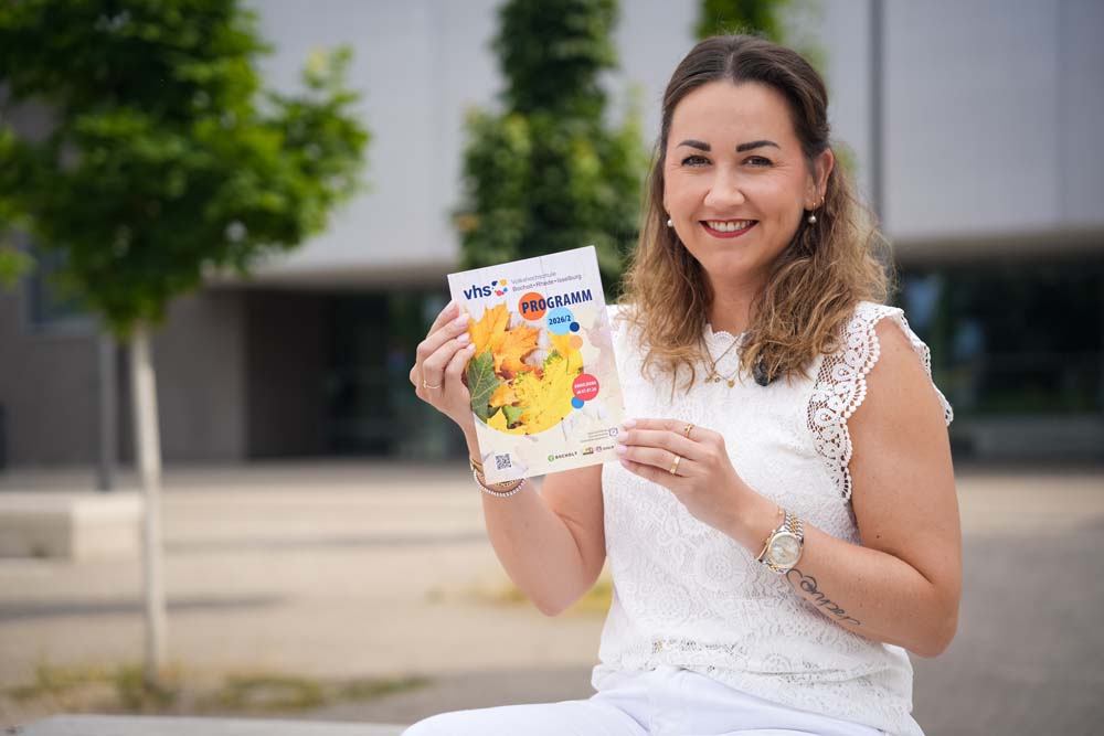 VHS-Leiterin Isabel Testroet zeigt das neue Programmheft für das zweite Halbjahr 2026