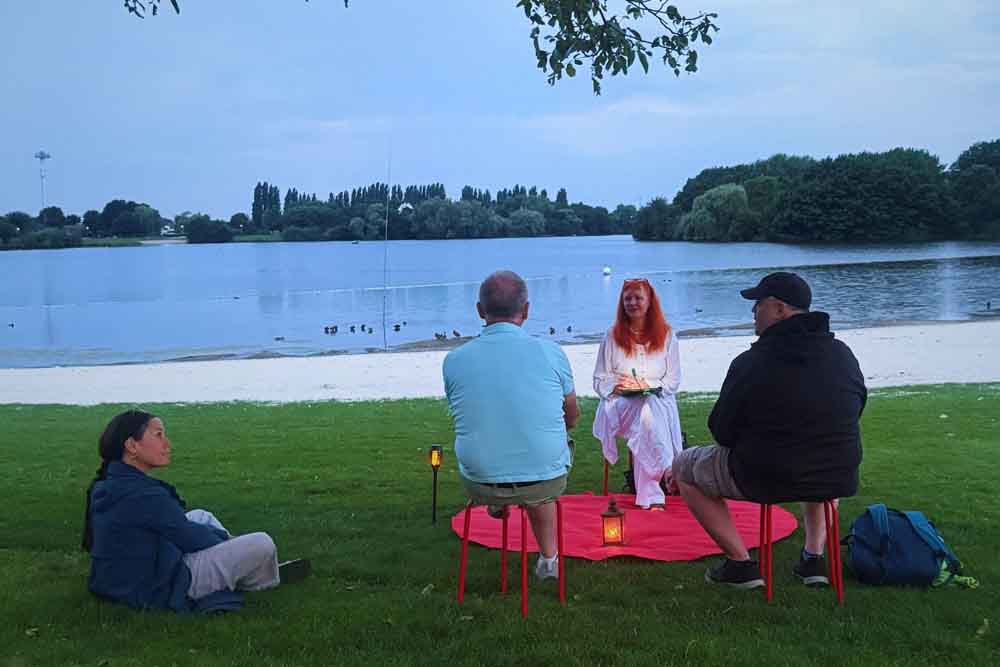 Teilnehmer bei „(Ge)Dicht an die Nacht" sitzen am Aasee