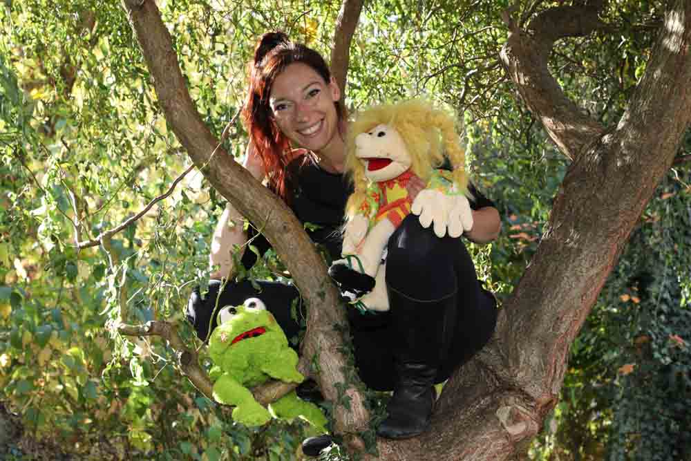 Theresa Tschira sitzt mit Puppen in einem Baum