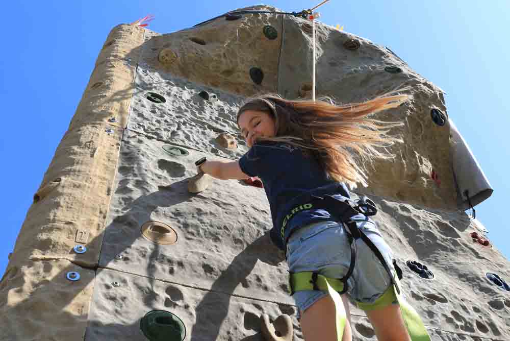 Mädchen hängt an Kletterwand