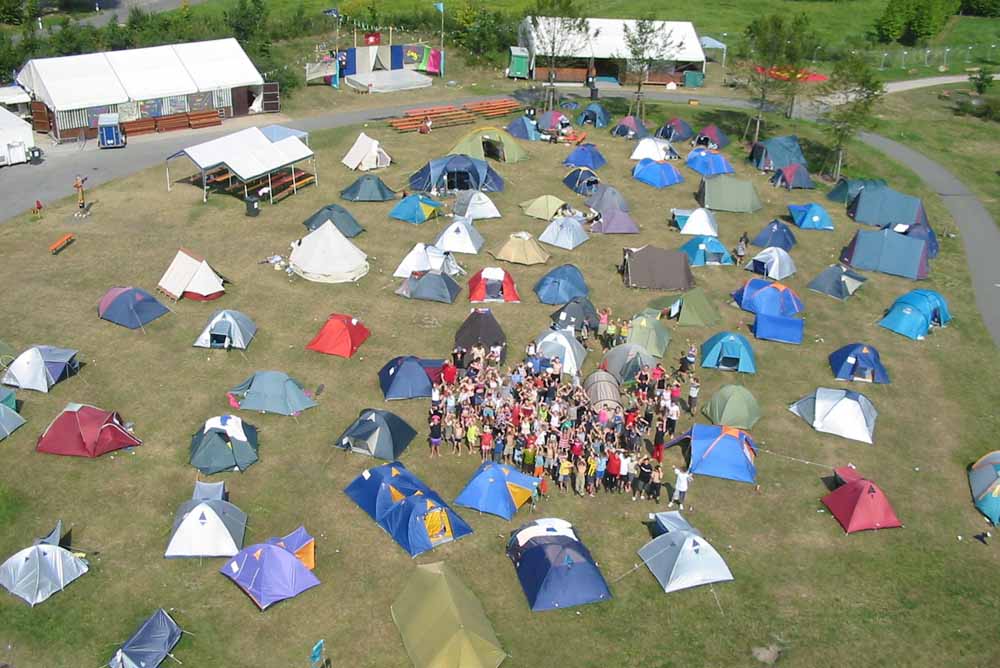 Luftbild: Gruppe von Kindern mit Zelten
