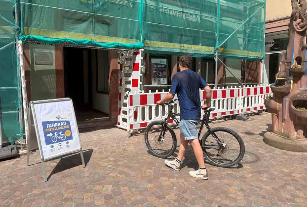 Mann schiebt Fahrrad in die neue Anlage