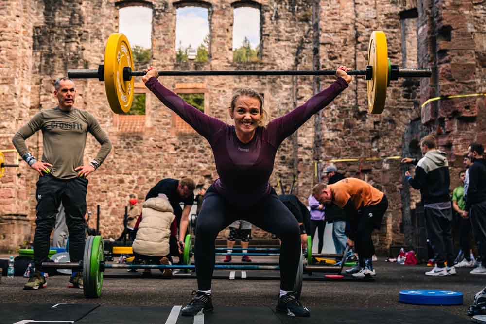 Frau beim Gweichtheben - andere Sportler im Hintergrund