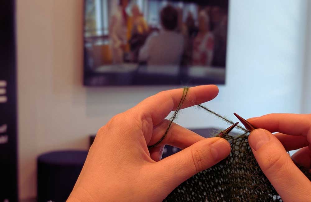 Person strickt vor dem Fernseher