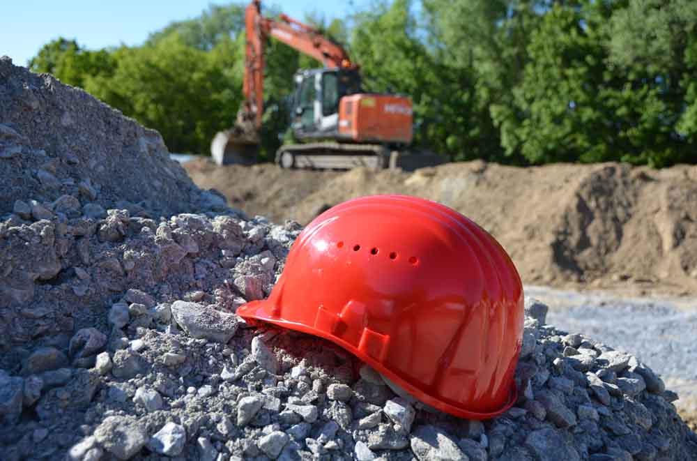 Schutzhelm liegt auf einer Baustelle auf einem Steinhaufen