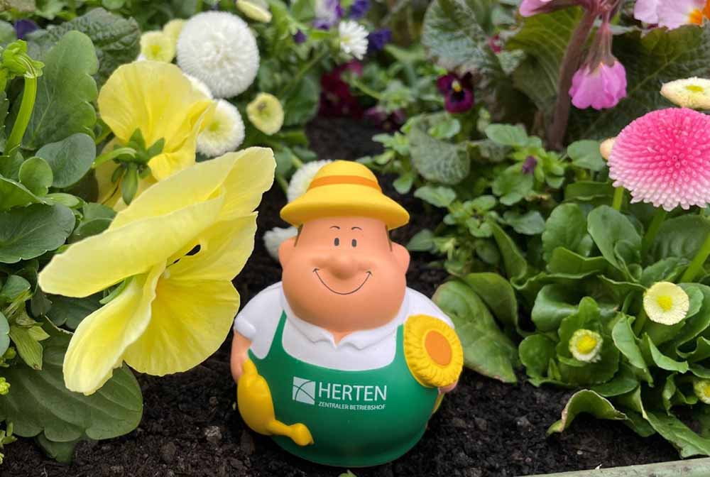 Gärtner-Figur steht in einem Blumenbeet