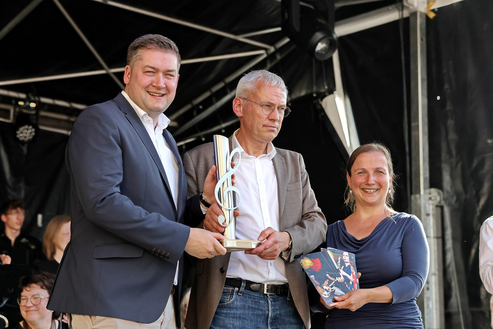 Ersten Stadtrat Kai-Uwe Hirschheide, der den Staffelstab von Wolfsburg (Austragungsort des 7. Regionalen Musikfestes 2024) an Oberbürgermeister Dr. Thorsten Kornblum übergibt und Juliane Gaube von der Kontaktstelle Musik Region Braunschweig als Organisatorin