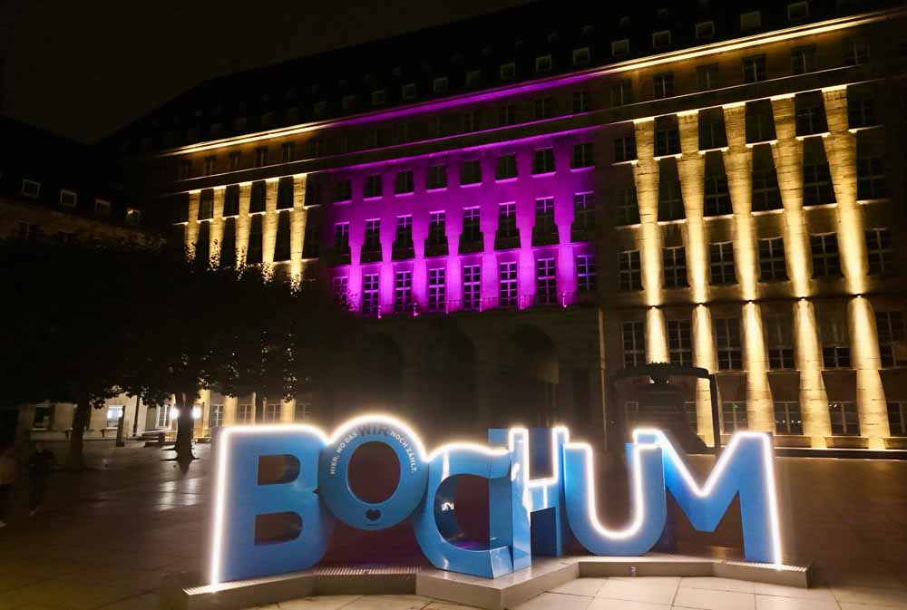 Rathaus in Bochum illuminiert mit Schriftzug "Bochum" im Vordergrund