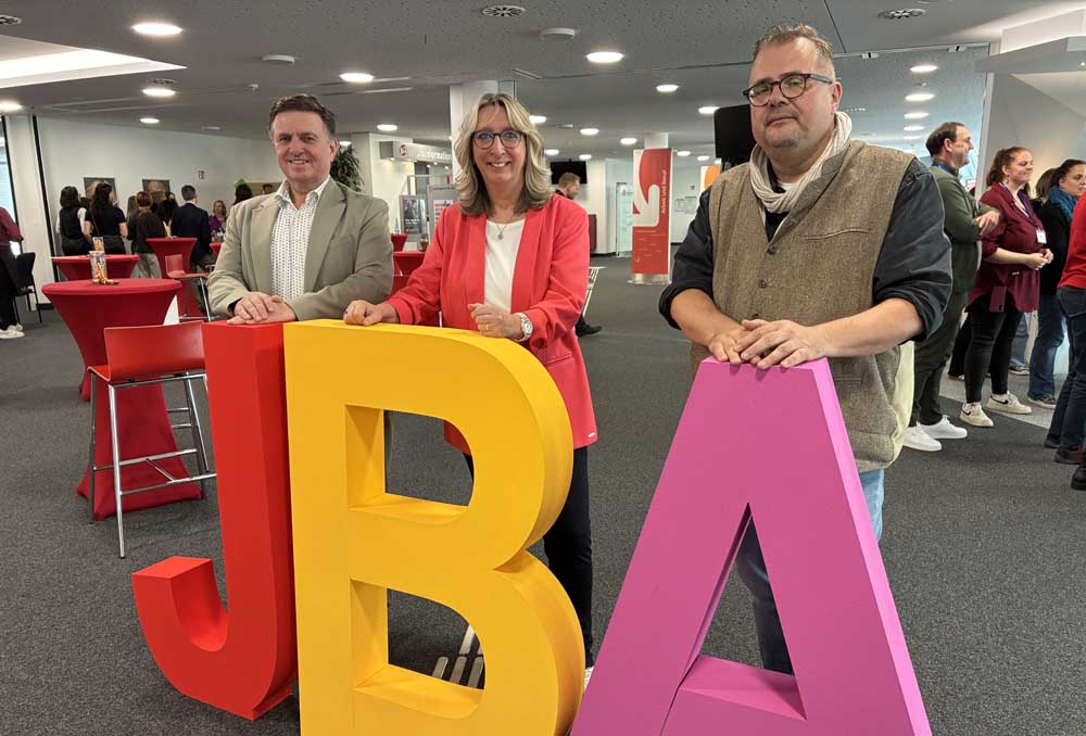 Ingo Zielonkowsky (Jobcenter Düsseldorf), Birgitta Kubsch-von Harten (Agentur für Arbeit Düsseldorf) und Stephan Glaremin (Amt für Soziales und Jugend) stehen hinter einem JBA-Logo