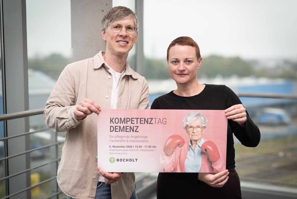 Geschäftsbereichsleiter Christian Tewiele und Marie-Therese Brand vom Bereich Rente, Senioren, Betreuungen und Ehrenamt mit Plakat zur Veranstaltung