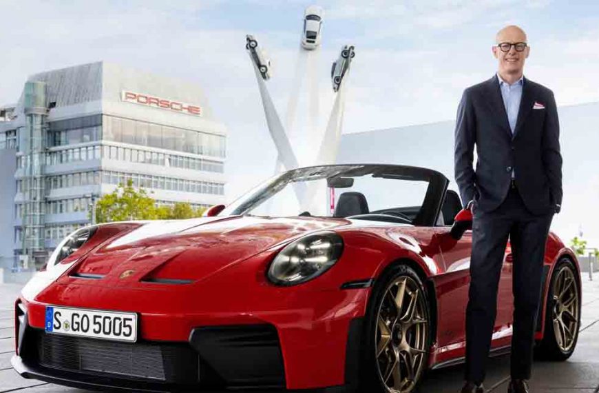 Dr. Michael Leiters steht neben einem Porsche, vor der Zentrale von Porsche