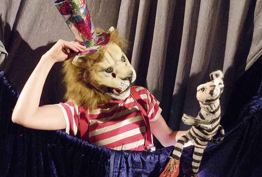Frau mit Löwenkopf hält Handpuppe